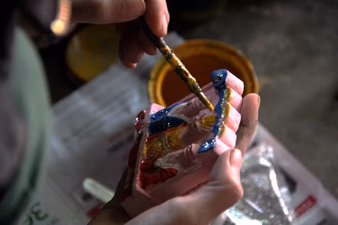  A worker in central Vietnam paints a small relief sculpture of Vietnamese Kitchen Gods. Millions of them are made every Tet. Photo by VnExpress