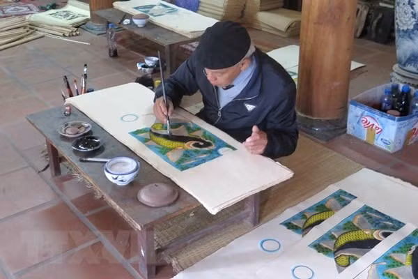 Artisan Nguyễn Đăng Chế finishes a Đông Hồ painting called Cá Chép Trông Trăng (Moonlight Carp). — VNA/VNS Photo