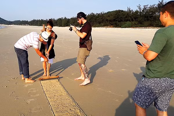 Foreign tourists try catching clams on the sand
