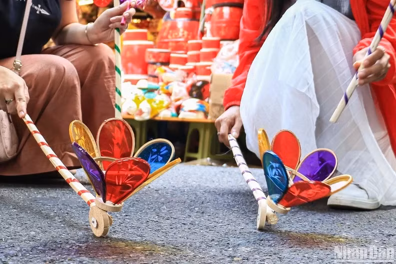 "Den cu” (spinning wheel lantern) is one of the traditional Mid-Autumn toys. Making a “den cu” takes a lot of work. The process starts with the sharpening of bamboo sticks to smaller and thinner ones. These are knit together into a spinning-top shape. Then, colourful paper is stuck to the frame. Next is to attach a wooden wheel to the frame and tie it with steel wire core so that the lamp can move when pushed back and forth.