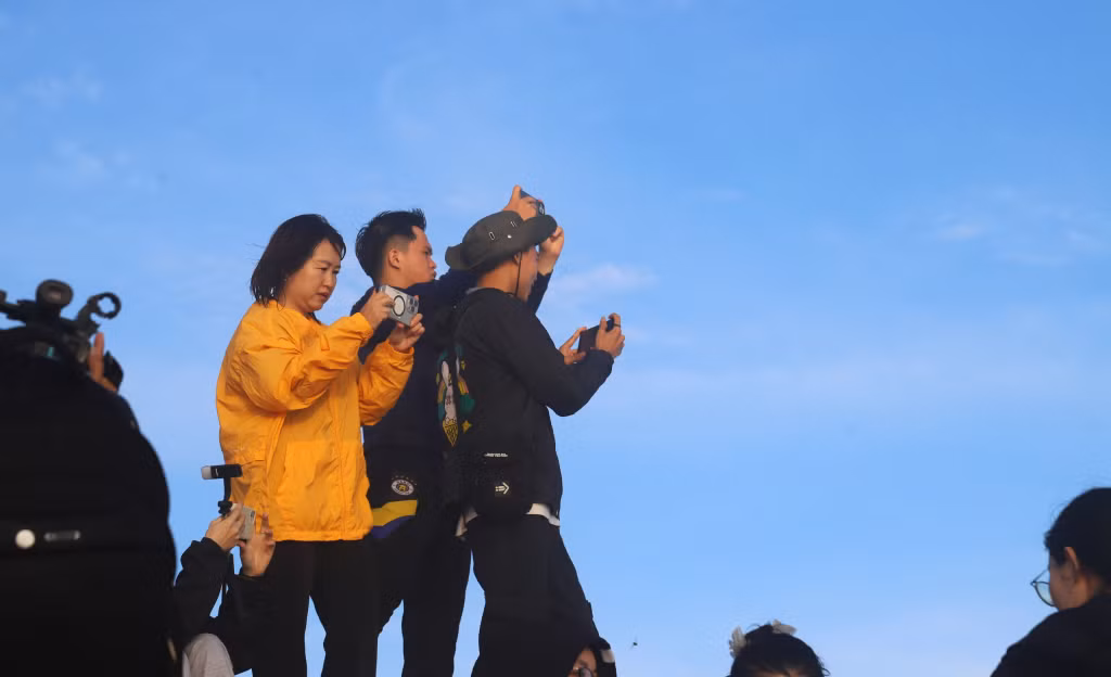 As the first light of dawn appears, many young visitors excitedly capture every memorable moment.