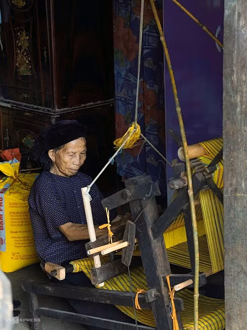 Nong Thi Phuong, 81, uses a loom to weave fabric.
