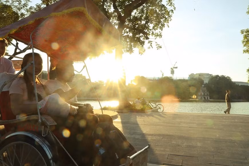 A visitor tours Hoan Kiem Lake basking in autumn sunshine while taking a cyclo. (Photo: VNA)