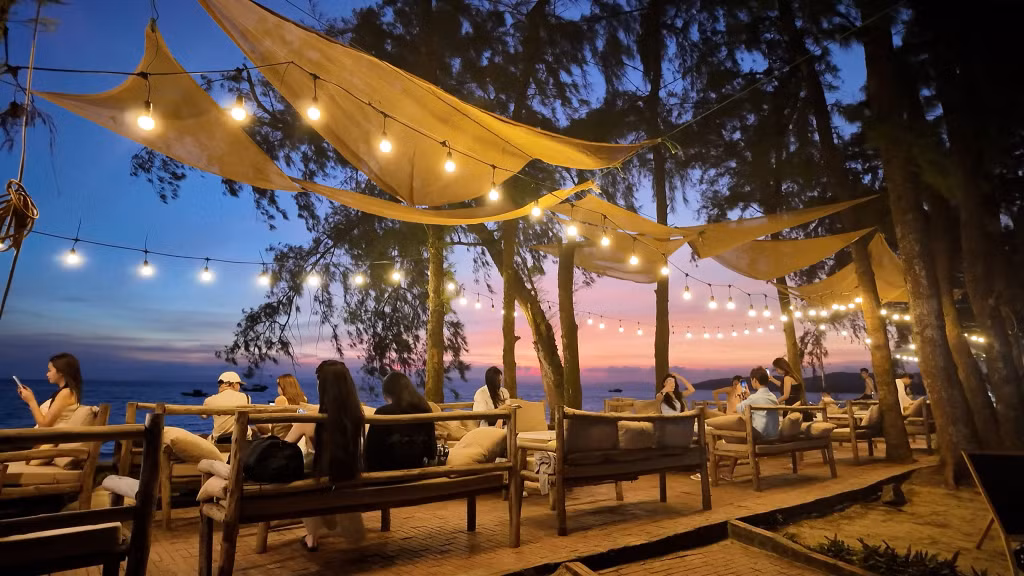 Tourists enjoy the beauty of sunset from a café close to the beach.