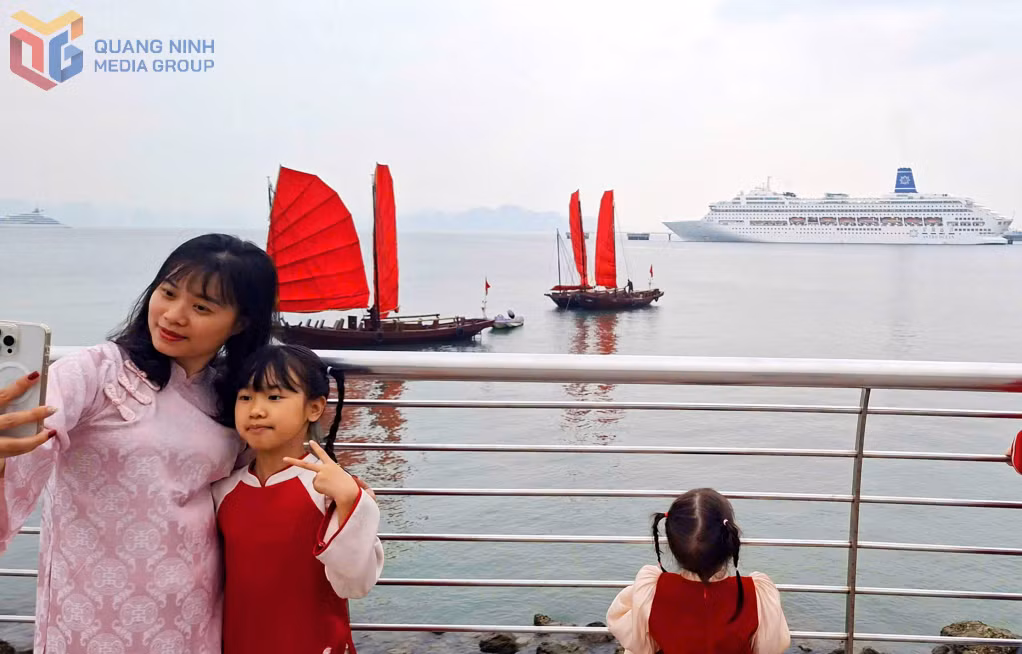 Visitors enjoy posing with traditional red-sailed boats along Ha Long Bay.