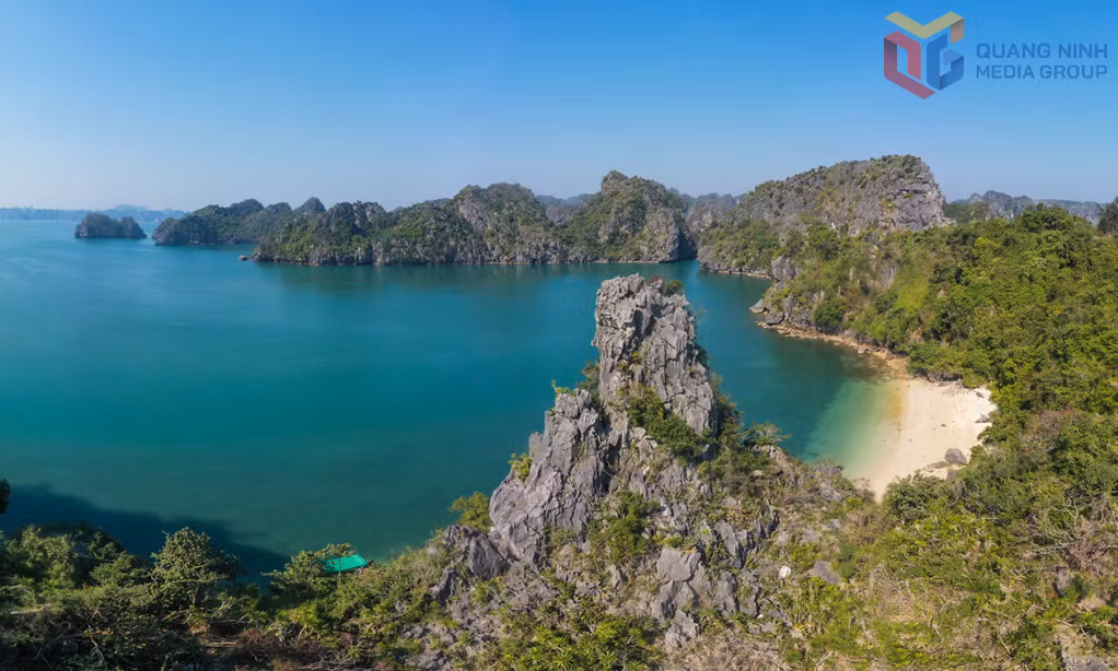 Towering limestone formations stand guard over a tranquil sandy shore at Vung Vieng, reflecting the serene and contemplative beauty of Ha Long Bay.