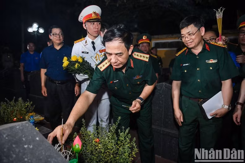 General Phan Van Giang offers incense at a tomb.