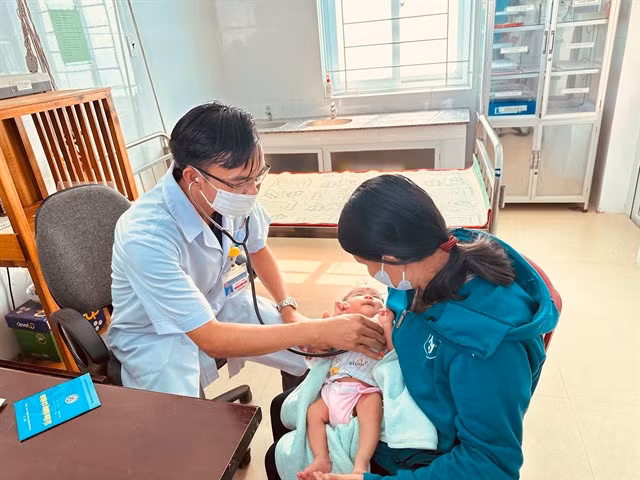 Dr Hoàng Ngọc Đức, head of Cam Tuyền Health Centre, examines a baby patient at the centre in Cam Lộ District, Quảng Trị Province.