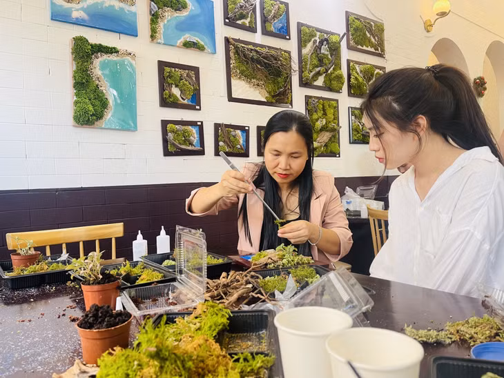 Ms. Nguyen Thanh Hau (left) guides young people to make moss paintings.
