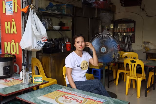Lê Thị Hà sits by a fan as high temperatures arrive early in the capital. VNS Photo Vân Nguyễn