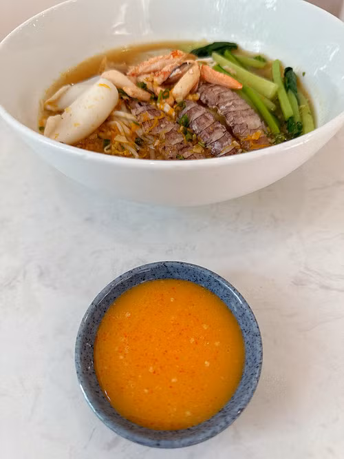 A bowl of red chili salt sauce is served with a portion of crab noodle at Muoi Ot Do restaurant. Photo by Han Tin