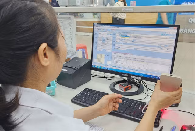 A health official in HCM City scans an electronic health record code on a VNeID application. — VNA/VNS Photo