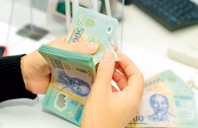 A bank teller counts cash in a transaction office in Hà Nội. Interest rates for one-week, two-week and one-month loans in the interbank market have stayed at the lowest level in the past eight months. Photo vietnamfinance.vn