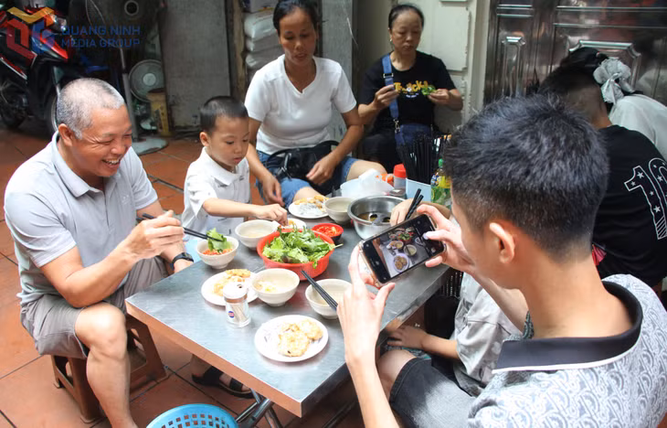 Tourists eagerly snap photos of the banh cuon with squid cakes before enjoying the dish.
