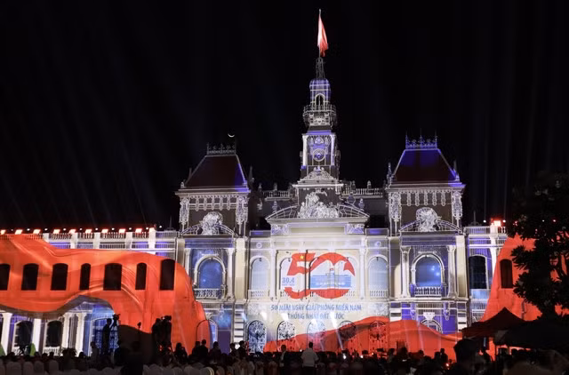 Onlookers enjoy a 3D Mapping projection of the symbol of 50 years of Southern Liberation and National Reunification in the city. — VNA/VNS Photo