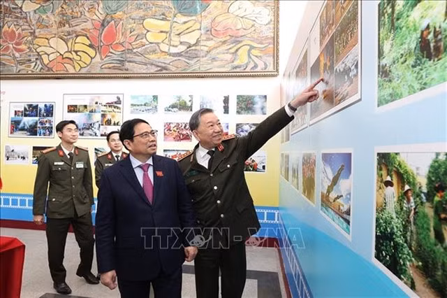 Prime Minister Phạm Minh Chính (left) and Minister of Public Security Tô Lâm look at photos of the police force's activities. — VNA/VNS Photo Dương Giang