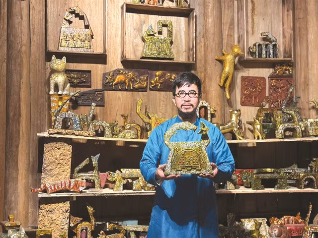 Sculptor Nguyễn Tấn Phát is pictured with the feline statue that won third prize in the Việt Nam Handicraft Design contest 2022. — Photo courtesy of the artist