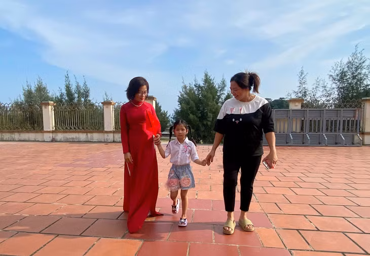 Tran Ngoc Anh, 6 year old, the youngest resident on Tran island, was taken to school by her mom and teacher.