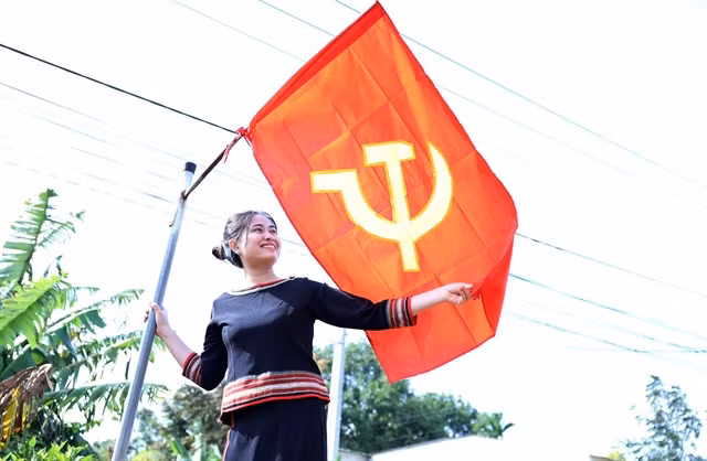 H'Hằng Êban, a local resident in Đắk Lắk Province hangs the flag of the Communist Party of Việt Nam on a street in her village. — VNA/VNS Photo Hoài Thu
