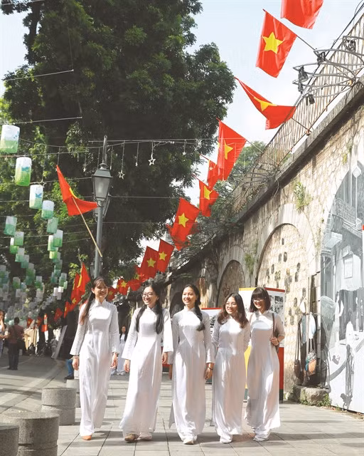 Young Hanoian women in áo dài (long dress) walk along a street. The city now has an annual Áo Dài Festival to honour the national traditional costume. VNS Photo Trương Vị
