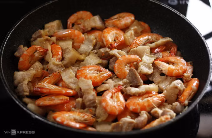 The cooked pork belly takes on a light brown hue, while cooked shrimps showcase a bright red color. Photo by VnExpress/Bui Thuy