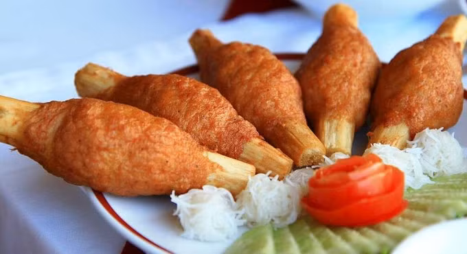 Chao tom, originating from Hue, central Vietnam, features shrimp paste wrapped around sugar cane, flavored with garlic and spices, and served with veggies, rice noodles, and fish sauce.