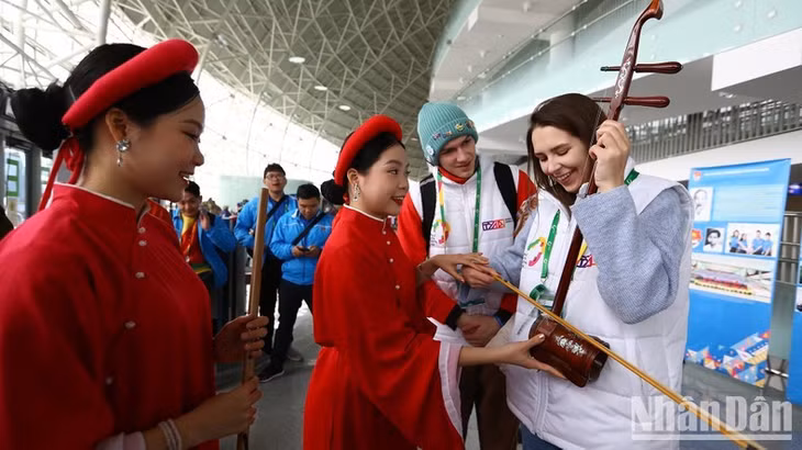 Liza trying to play a Vietnamese instrument under the instruction of artists from the Vietnam Music and Dance Theatre.