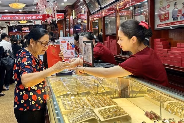 A customer shops for gold jewellery at a gold shop in Hai Bà Trưng District, Hà Nội. VNA/VNS Photo