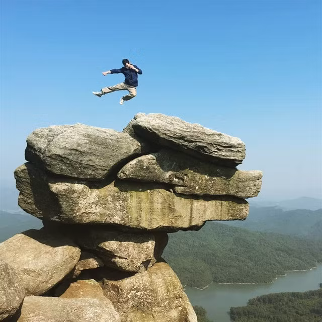 HIGH KICK: A young tourist shows off at the top of Chồng Mountain. - Photo ximgo.com