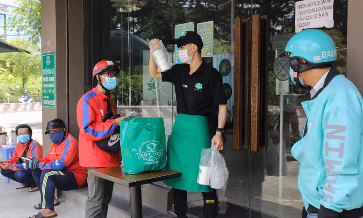 Shippers wait to pick up orders at a coffee shop in Ho Chi Minh City on September 16, 2021. Photo by VnExpress/Quynh Tran