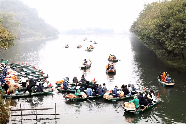 Tourists sitting on boats to discover Trang An Scenic Landscap Complex.