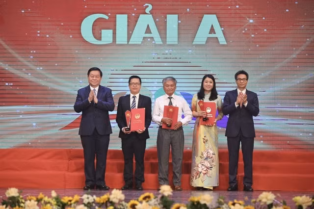 Chairman of the Party Central Committee’s Commission for Publicity and Education Nguyễn Trọng Nghĩa (first left) and Deputy Prime Minister Vũ Đức Đam (first right) presents the prizes to the representatives of the winning book. — VNA/VNS Photo Minh Quyết