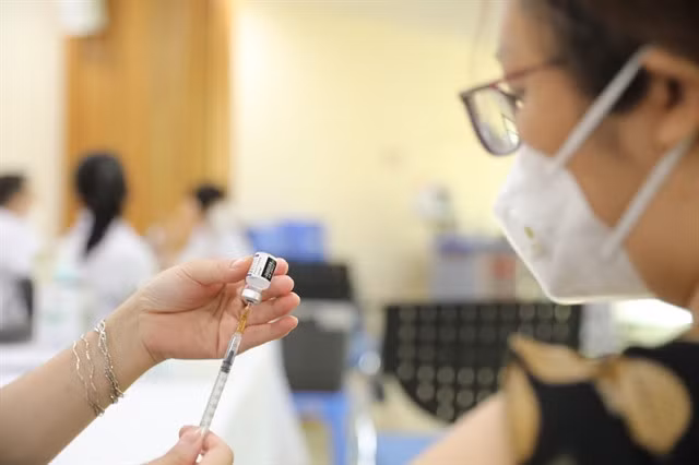 A State worker prepares to receive a fourth dose of COVID-19 vaccine.