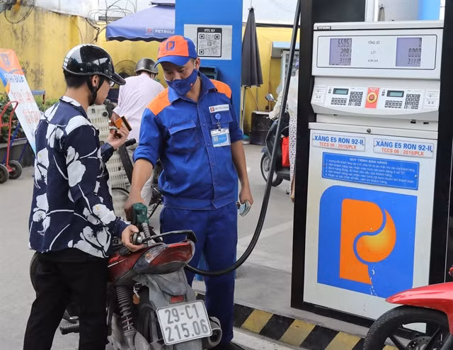 A driver gets his motorbike refilled at a fuel station.