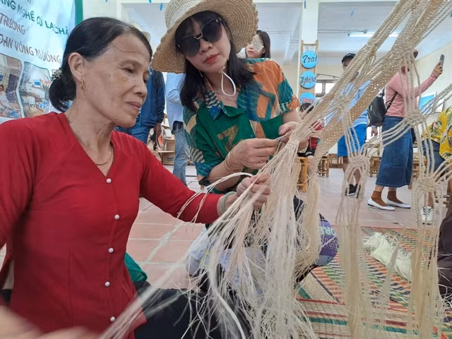 ECO PRODUCTS: A local weaver guides a tourist in making a bark tree hammock. The islands have banned the use of single-use plastic bags for two decades. VNS Photo Công Thành
