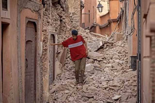 A Marrakesh resident clambers over the rubble of a home blocking one of the city's historic alleyways. — AFP/VNA Photo