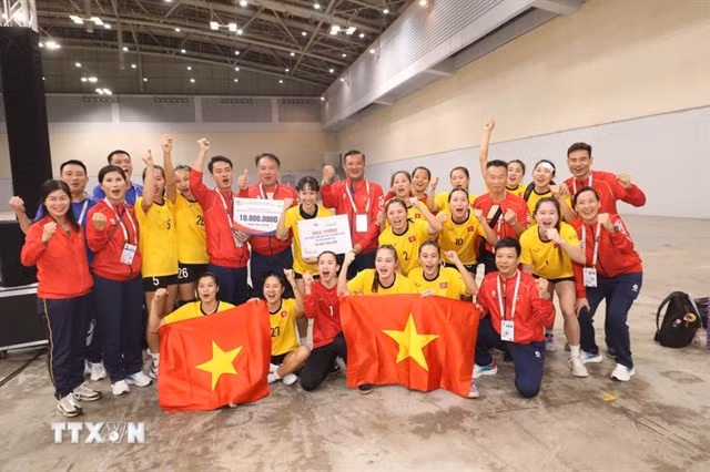 The players and coaching staff of the Vietnamese women's handball team celebrate with their gold medal.