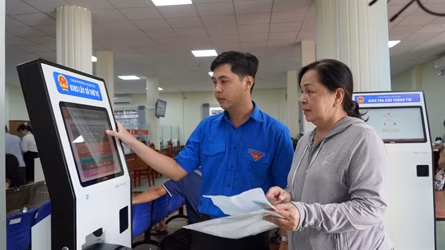 A youth volunteer helps a resident take her queue number at a public service centre in An Giang Province on July 22, three weeks after the two-tier local government system came into operation. — VNA/VNS Photo
