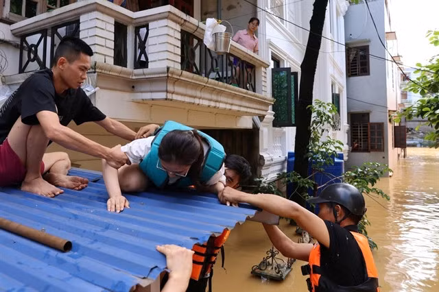 A rescue team helps a woman in the flood-hit province of Thái Nguyên after she was trapped in her home for two days by rising floodwaters.