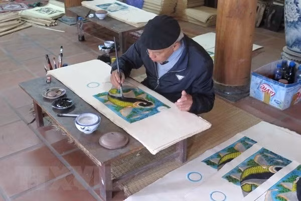 Artisan Nguyễn Đăng Chế finishes a Đông Hồ painting called Cá Chép Trông Trăng (Moonlight Carp). Photo VNA/VNS