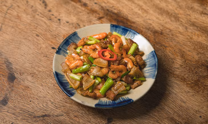 The stir-fried shrimp and pork belly boasts a reddish-brown color and a seared texture. Photo by VnExpress/Tung Le