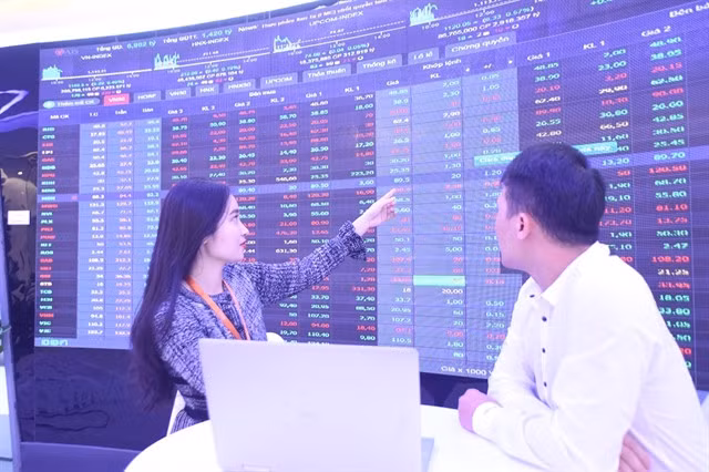 Investors watch the stock movements on a digital board. Photo thanhnien.vn