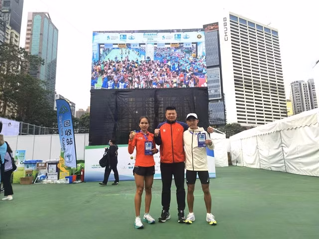Hoàng Nguyên Thanh (right), Hoàng Thị Ngọc Hoa (left) and their coach Trần Đoàn Minh Thiện pose for a photo after their remarkable running achievements. Photo of VAF