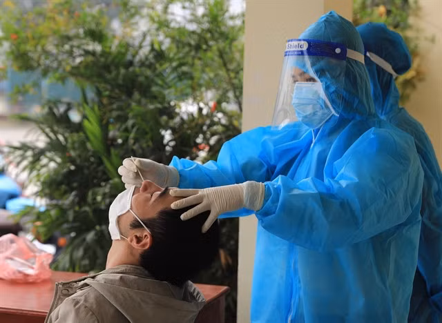 A medical worker in Hà Nội takes a sample of a resident for COVID-19 testing.