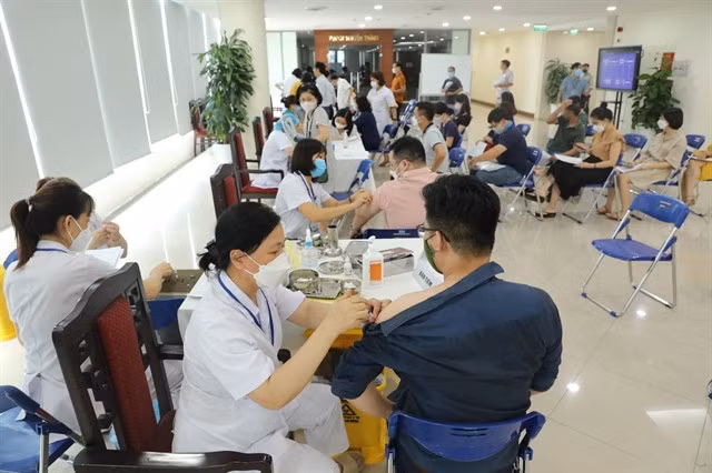 Booster shots (third and fourth doses) of COVID-19 vaccines are administered to Vietnam News Agency employees by Hoàn Kiếm District's health workers in early August 2022. — VNA/VNS Photo Minh Quyết