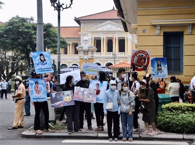 People hold placards in front of a court hall to call for justice for an eight-year-old girl beaten to death by his father's girlfriend. — VNA/VNS Photo