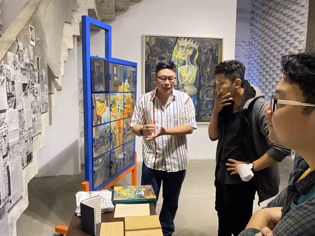 Artist Vũ Tuấn Việt (white shirt) with his work – VNS Photo Hồng Linh