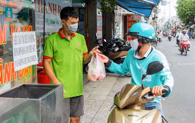 A shipper takes food from a shop to deliver to cusotmer in HCM City. Technology applications have played an important role in helping the food and beverage (F&amp;B) market in Việt Nam.