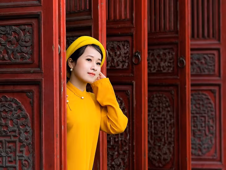 A woman wearing nhat binh dress takes photos inside the Imperial Citadel in downtown Hue. Photo by VnExpress/Duc Hieu