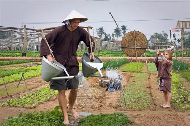 Foreign tourists try their hands at watering a garden in a traditional way at Trà Quế vegetable village in the coastal central province of Quảng Nam. — VNA/VNS Photo